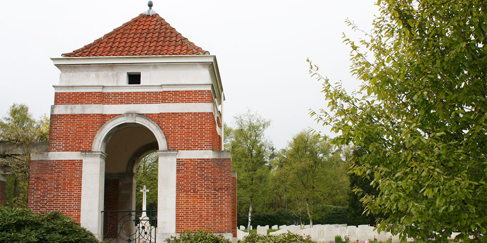 Een van de twee poortgebouwen van het ereveld van de begraafplaats. Op de achtergrond het Cross of Sacrifice. De Canadese Begraafplaats Holten