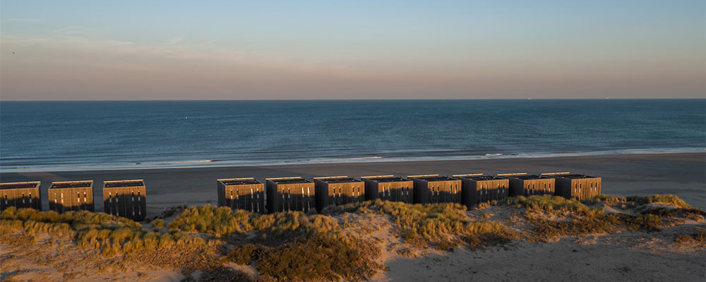 zicht vanaf de duinen op de beach villas aan het strand